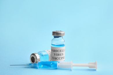 Chickenpox vaccine and syringe on light blue background. Varicella virus prevention