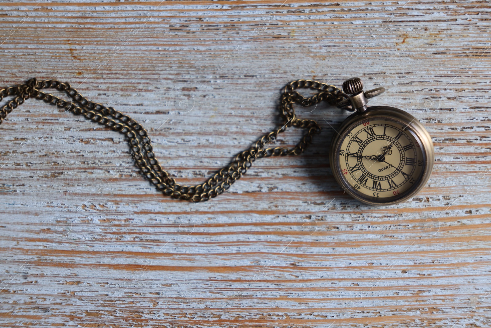 Photo of Pocket clock with chain on old wooden table, top view