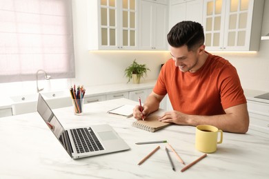 Photo of Man drawing in notebook at online lesson indoors. Distance learning