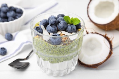 Photo of Tasty matcha chia pudding with coconut and blueberries on white table, closeup. Healthy breakfast