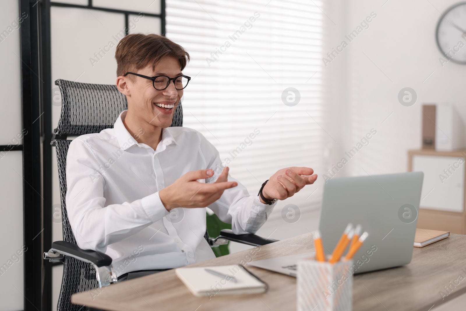 Photo of Man using video chat during webinar at wooden table in office