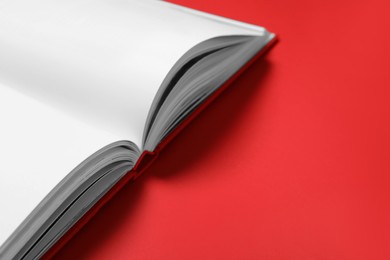 Photo of Open book on red background, closeup. Space for text