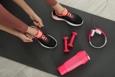 Photo of Top view of woman tying shoelaces on yoga mat