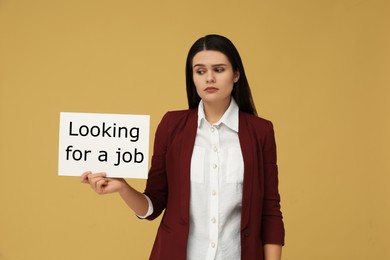 Unemployment problem. Unhappy woman holding sign with phrase Looking For A Job on pale orange background