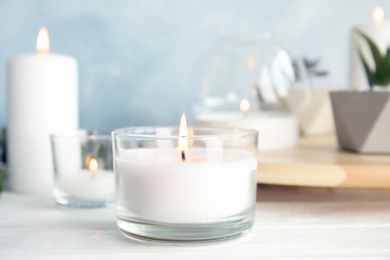 Burning aromatic candle in holder on table