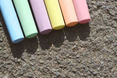 Photo of Colorful chalk sticks on asphalt, flat lay. Space for text