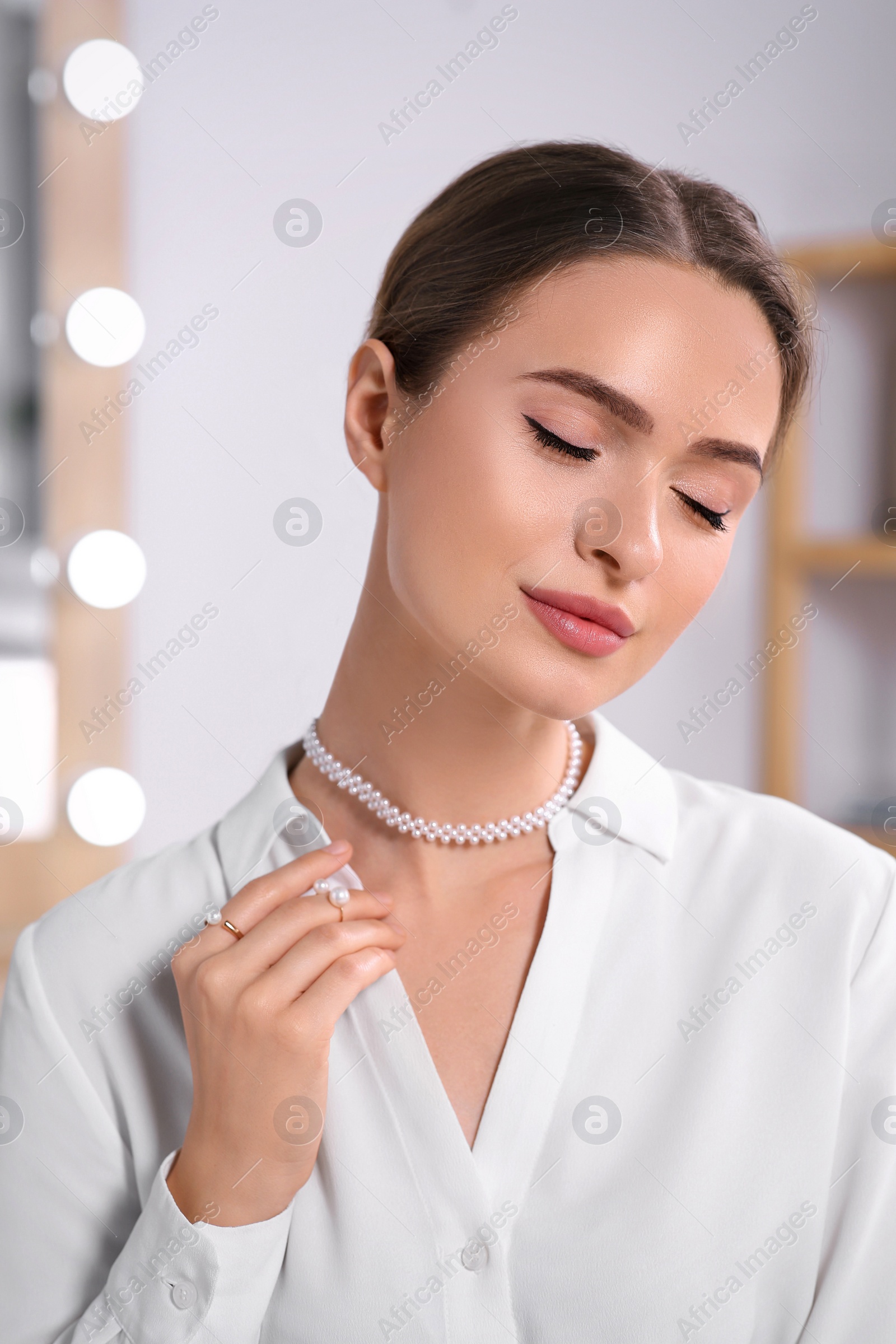 Photo of Young woman wearing elegant pearl jewelry indoors