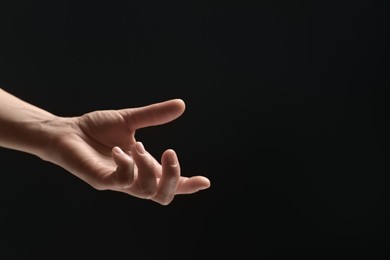 Photo of Woman holding something in hand on black background, closeup. Space for text