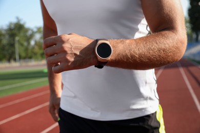 Photo of Man with fitness tracker running at stadium, closeup