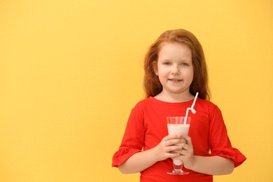 Photo of Little girl with glass of delicious milk shake on color background