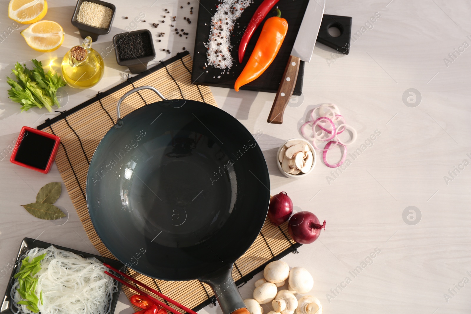 Photo of Wok, chopsticks and different products on white wooden table, flat lay. Space for text