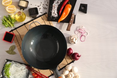 Photo of Wok, chopsticks and different products on white wooden table, flat lay. Space for text