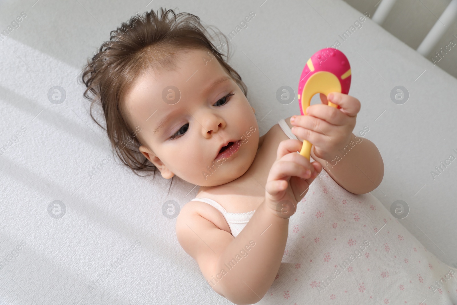 Photo of Cute little baby with toothbrush in comfortable crib, top view