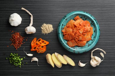 Flat lay composition with cabbage kimchi and ingredients on black wooden table