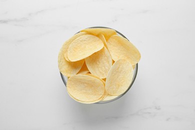Photo of Bowl with delicious potato chips on white marble table, top view