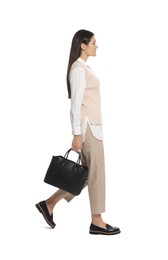 Young woman with stylish leather bag walking on white background