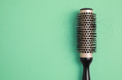 Photo of Professional brush with lost hair on green background, top view. Space for text