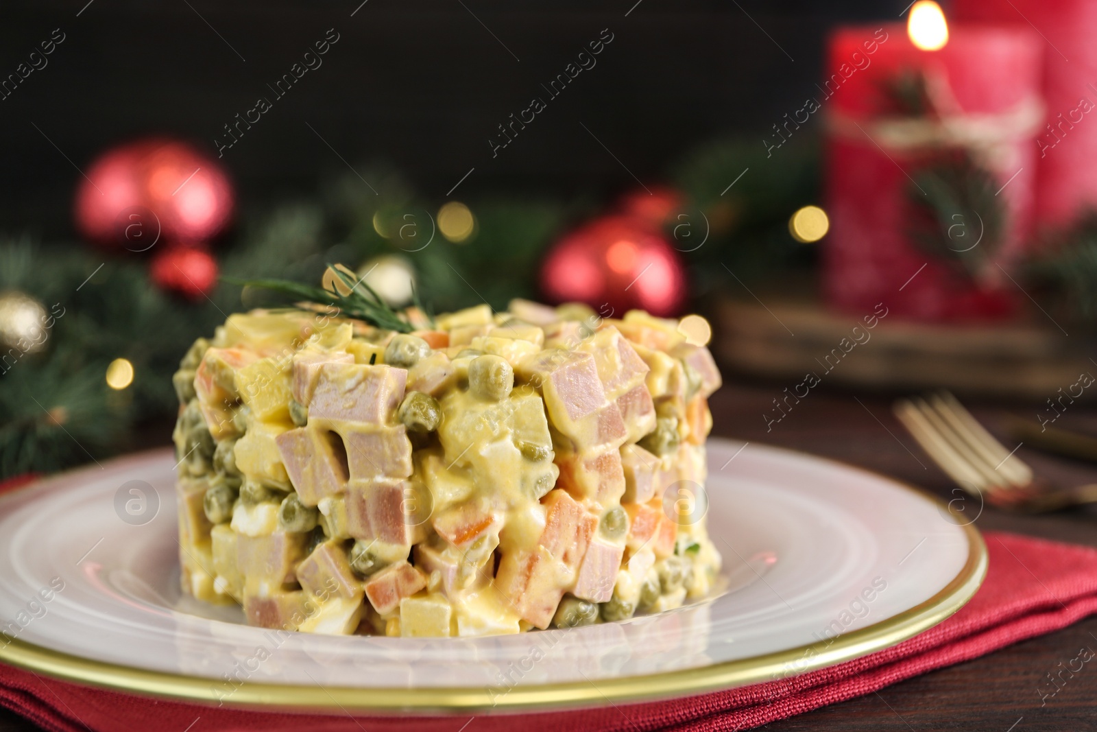 Photo of Traditional russian salad Olivier served on wooden table, closeup