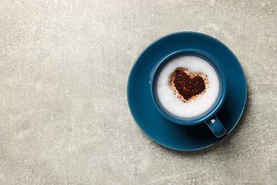 Cup of aromatic coffee with heart shaped decoration on light grey table, top view. Space for text