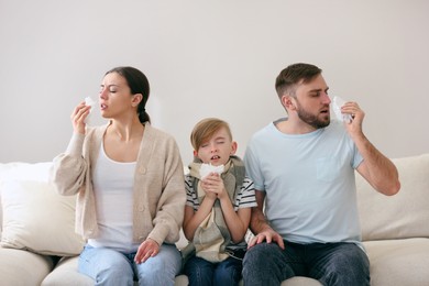 Photo of Family suffering from runny nose on sofa at home
