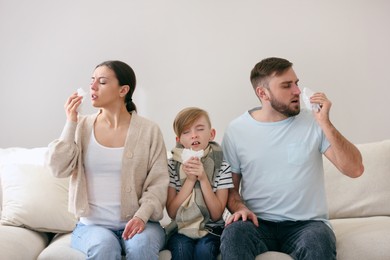 Family suffering from runny nose on sofa at home