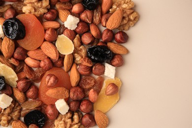 Photo of Different tasty nuts and dried fruits on beige background, flat lay. Space for text