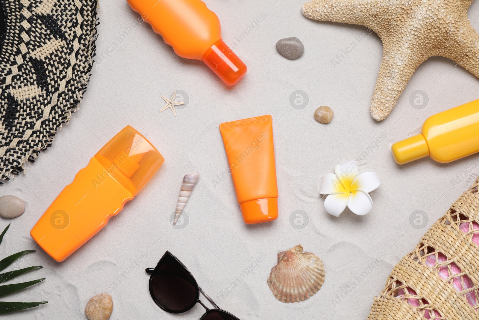 Photo of Flat lay composition with sun protection products on sand