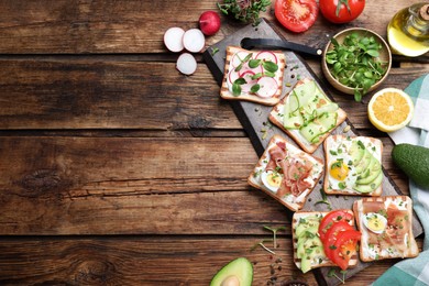 Different delicious sandwiches with microgreens on wooden table, flat lay. Space for text