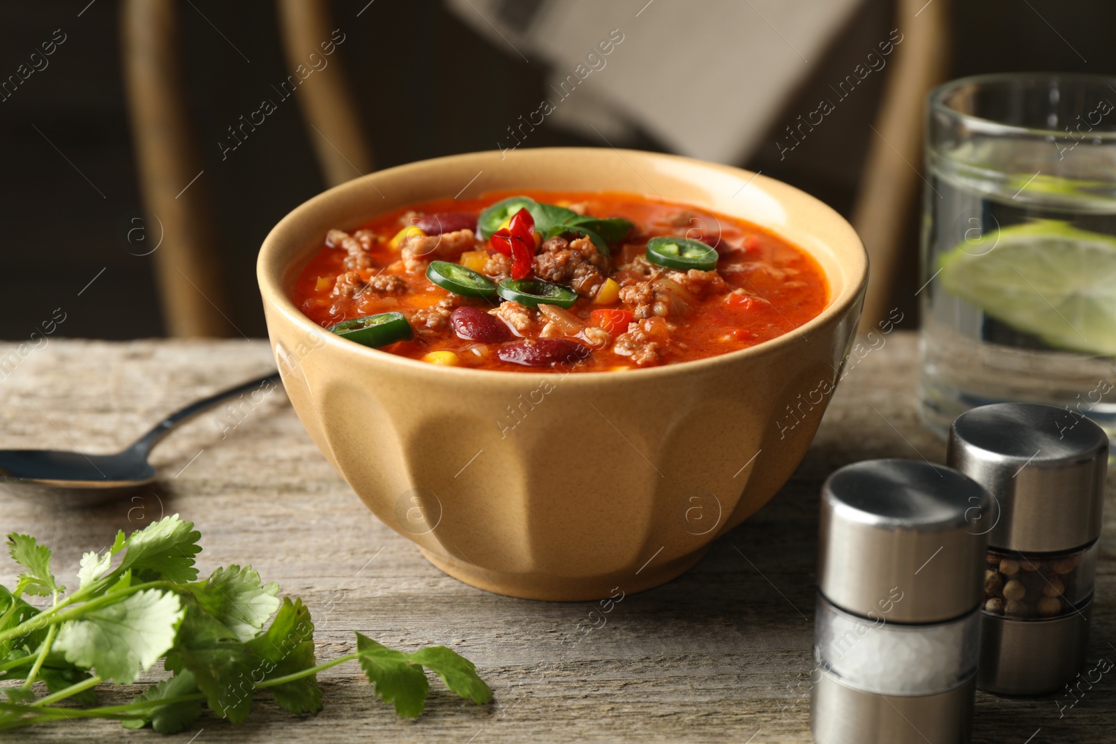 Photo of Bowl with tasty chili con carne served on wooden table
