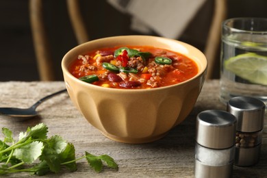 Bowl with tasty chili con carne served on wooden table