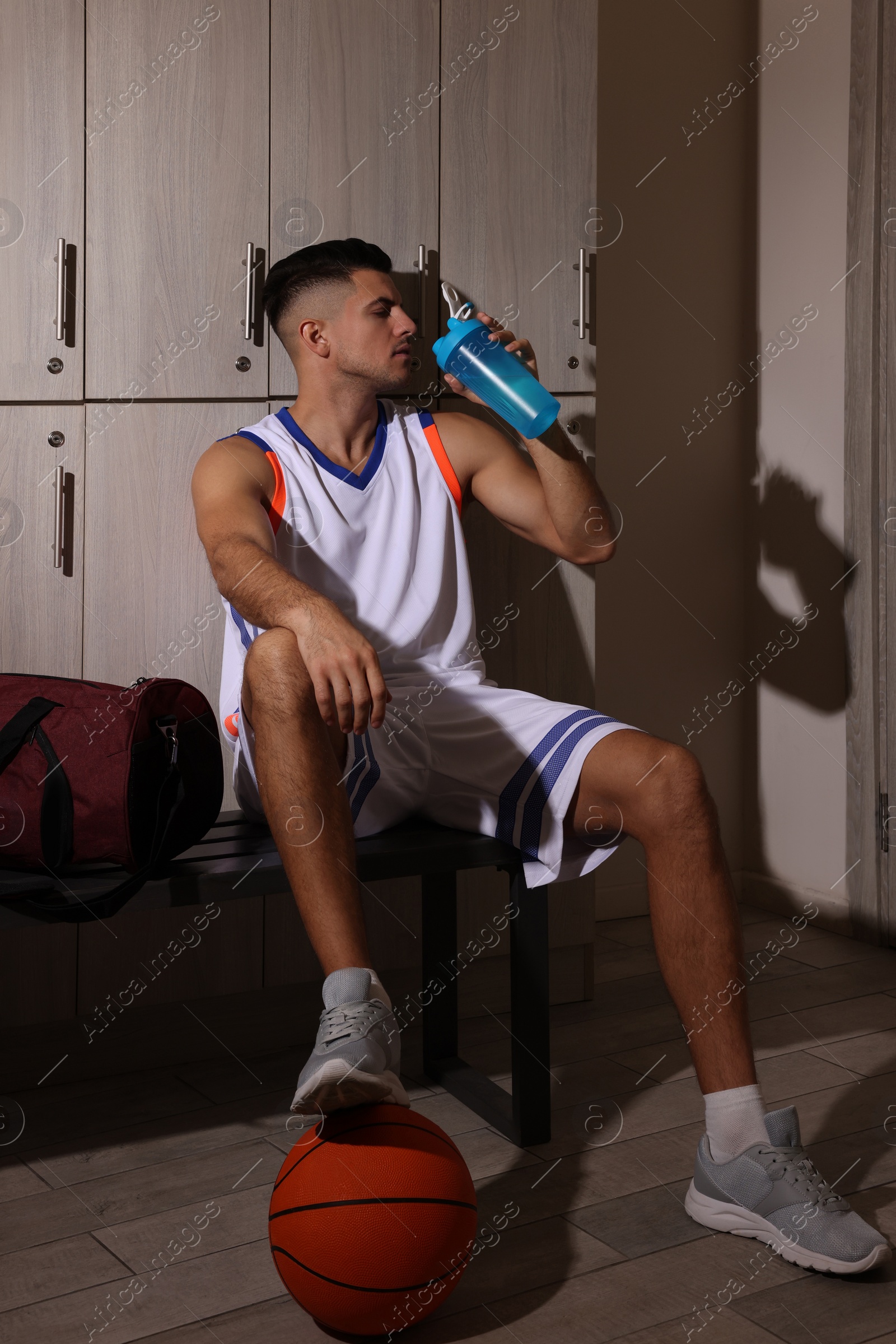 Photo of Handsome man drinking water in locker room