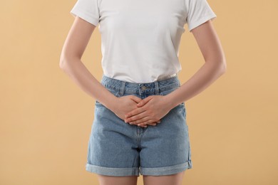 Photo of Woman suffering from cystitis on beige background, closeup