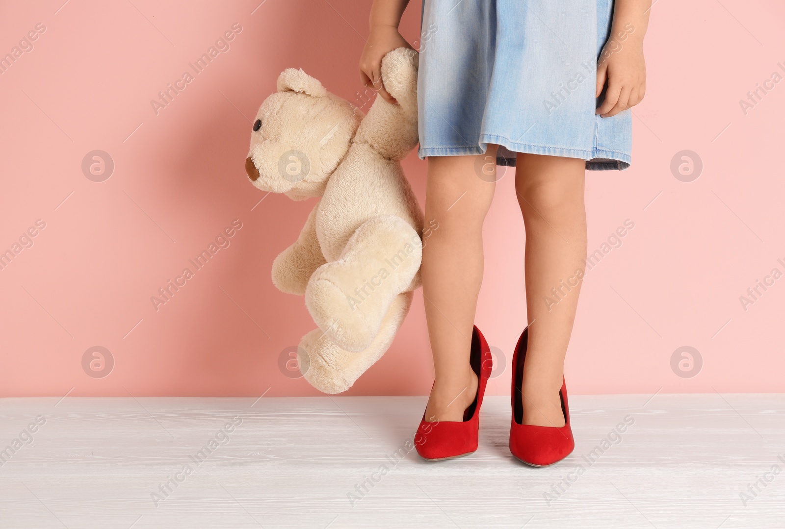 Photo of Little girl in oversized shoes near color wall with space for text, closeup on legs