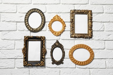 Photo of Blank vintage frames hanging on white brick wall. Mockup for design
