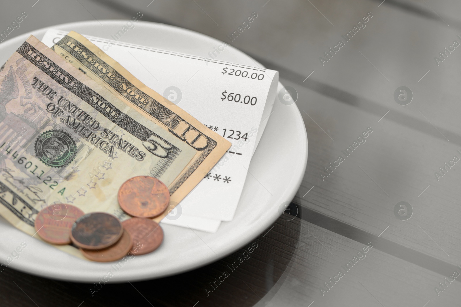 Photo of Tips and receipt on wooden table in outdoor cafeteria, closeup