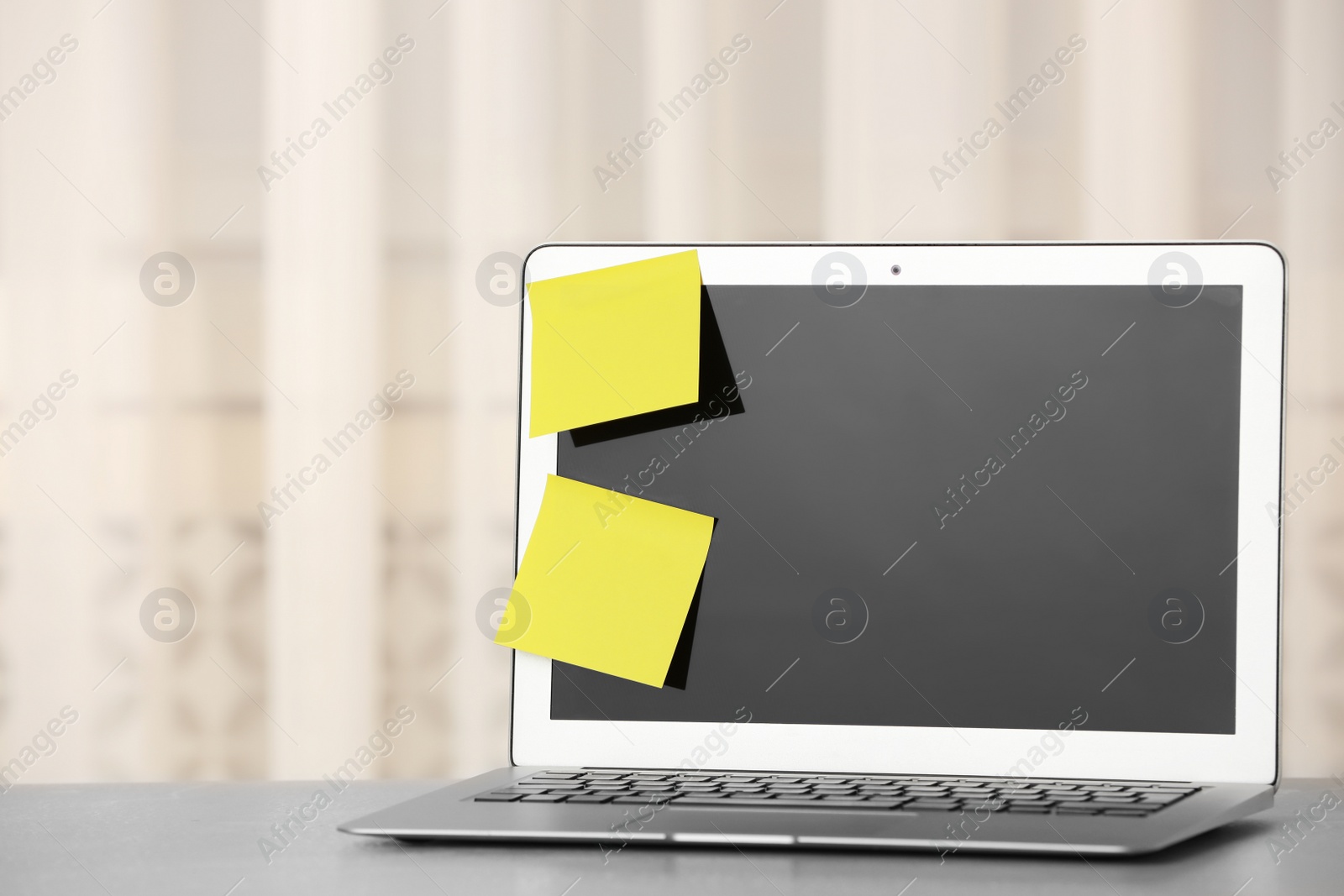 Photo of Laptop with empty sticky notes on table indoors. Space for text