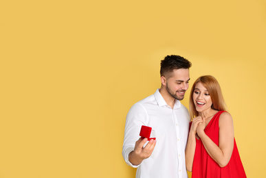 Photo of Man with engagement ring making marriage proposal to girlfriend on yellow background