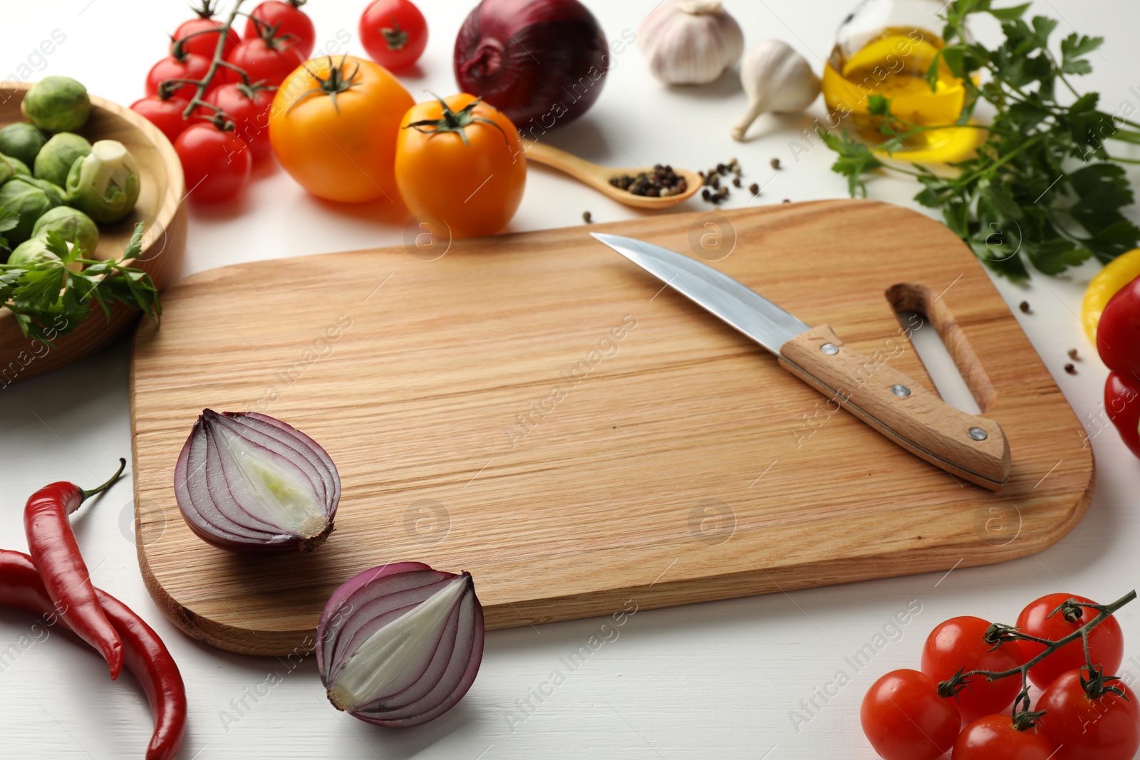 Photo of Cutting board with different vegetables and knife on white wooden table, closeup