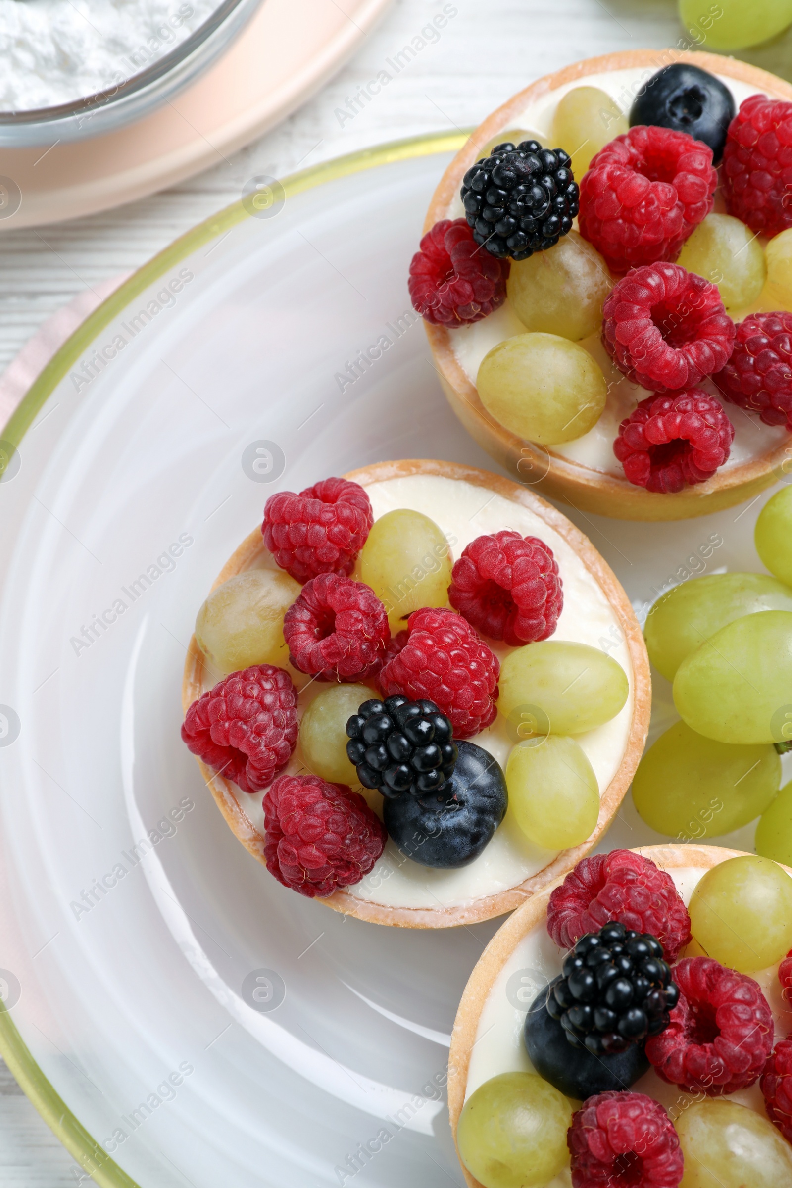 Photo of Delicious tartlets with berries on white table, top view