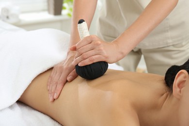 Photo of Young woman receiving herbal bag massage in spa salon, closeup