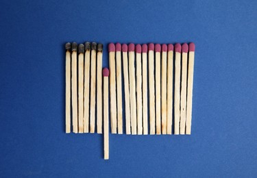 Flat lay composition with burnt and whole matches on blue background