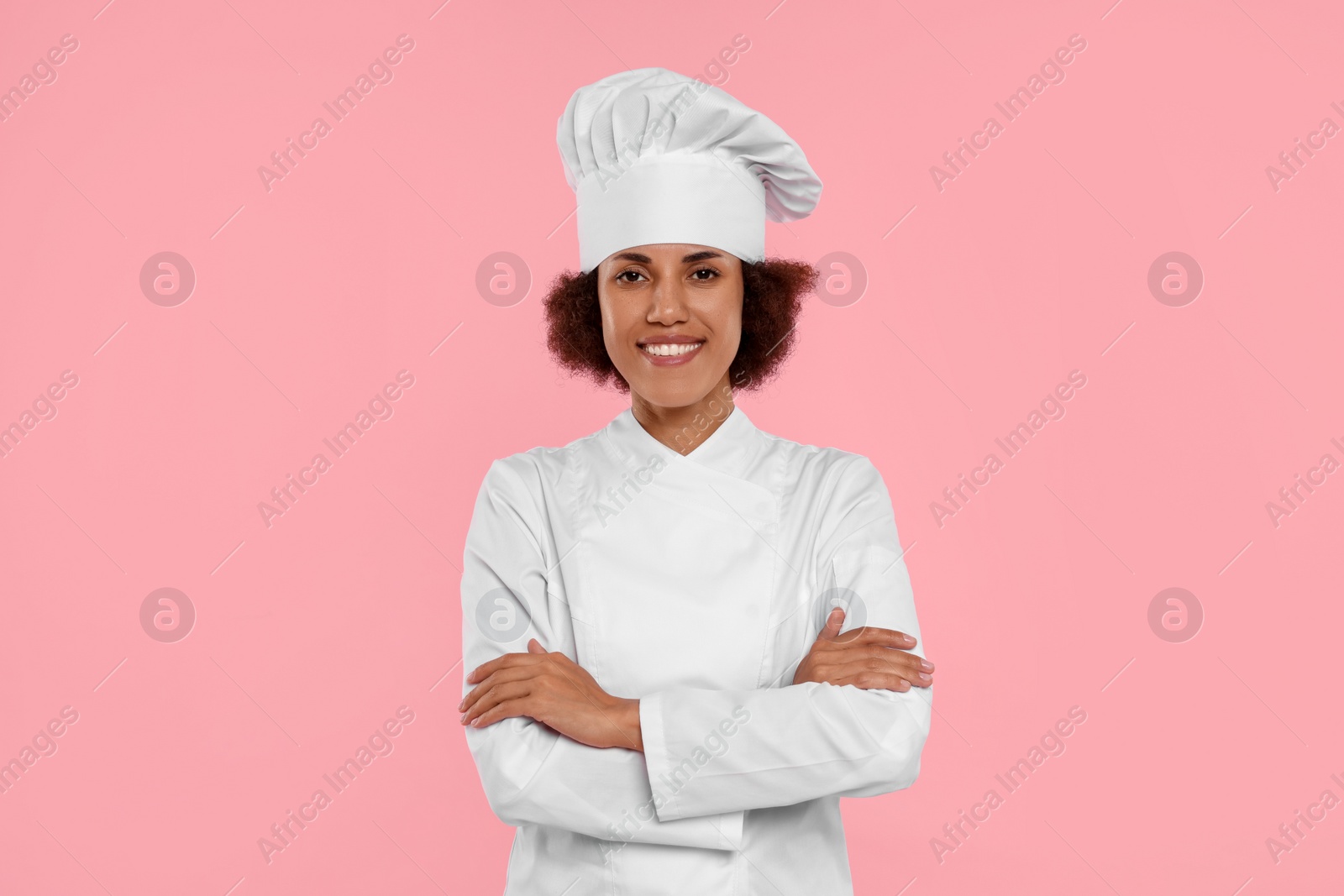 Photo of Portrait of happy female chef in uniform on pink background