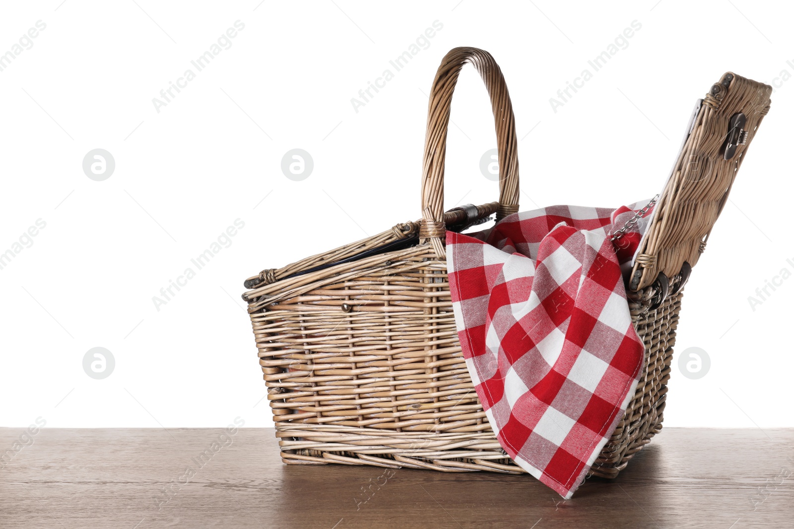 Photo of Wicker picnic basket and checkered blanket on wooden table against white background