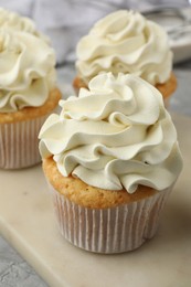 Photo of Tasty cupcakes with vanilla cream on grey table, closeup