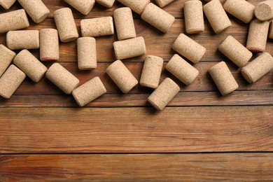 Photo of Many corks of wine bottles on wooden table, flat lay. Space for text