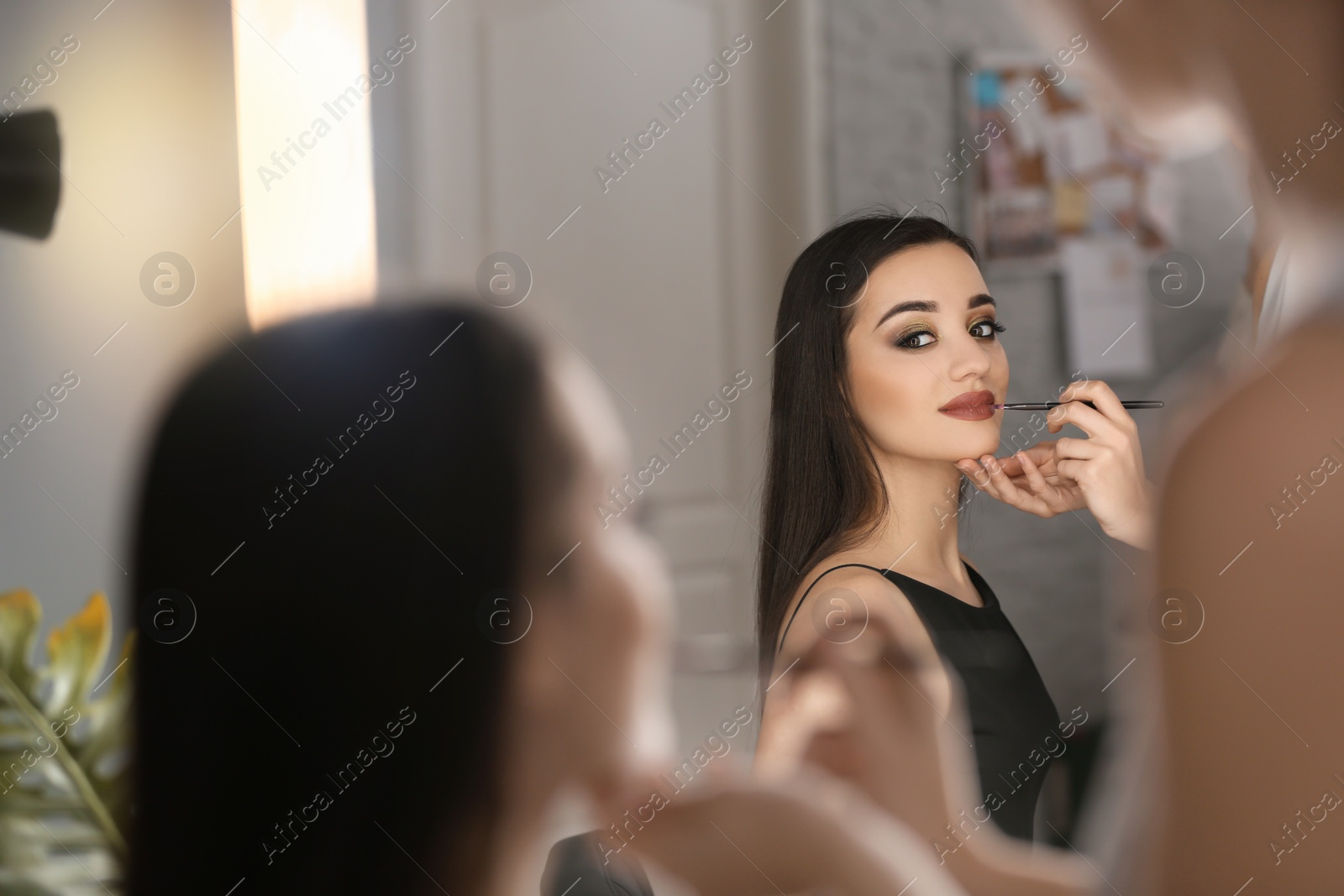 Photo of Professional visage artist applying makeup on woman's face in salon