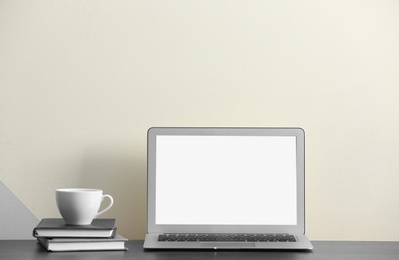 Photo of Modern laptop on desk near color wall, space for design. Home workplace