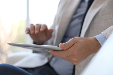 Photo of Businessman working with modern tablet in office, closeup