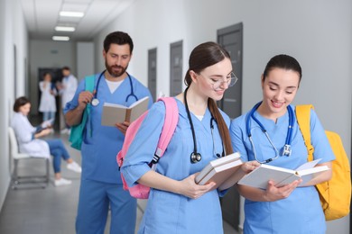Photo of Smart medical students with books in college hallway, space for text
