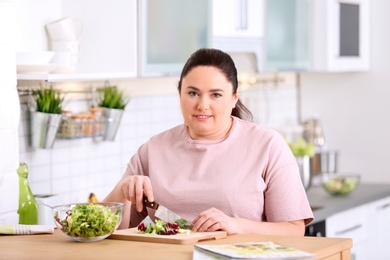 Photo of Overweight woman preparing salad in kitchen. Healthy diet